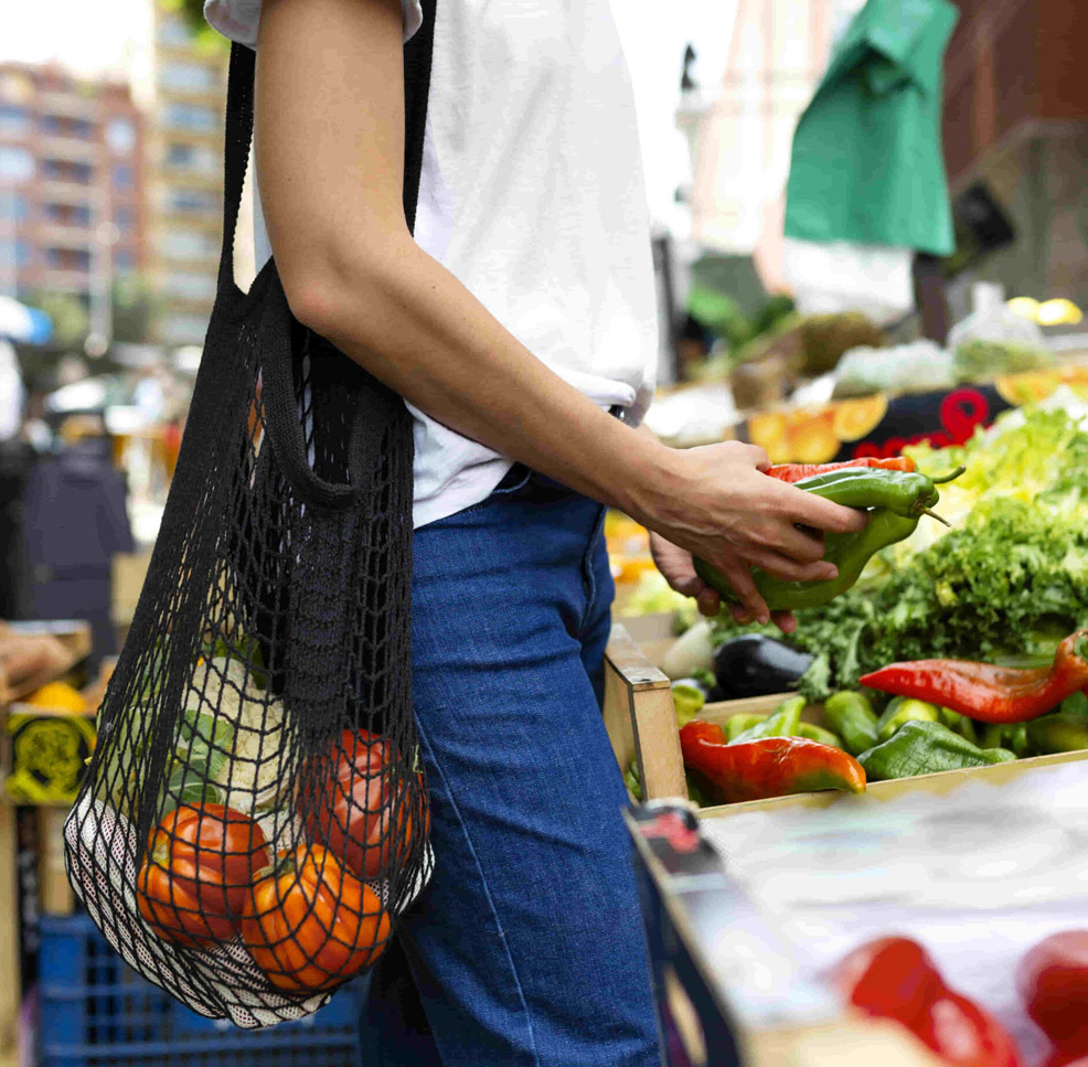 Frau beim Einkaufen von Gemüse in Mehrwegtasche