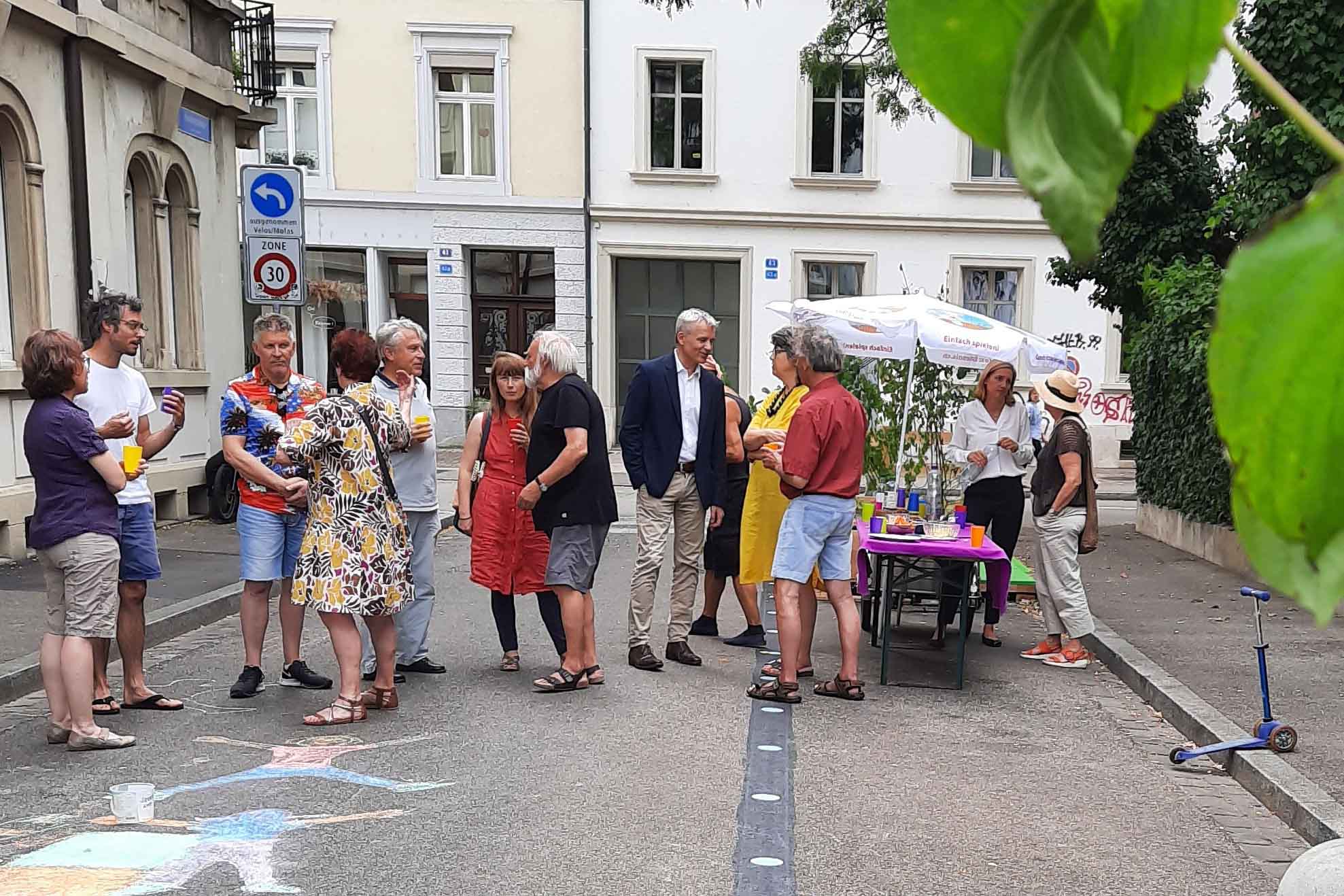 Eine Menschengruppe steht auf der Strasse vor einem Stand an der Veranstaltung "Summeregge".