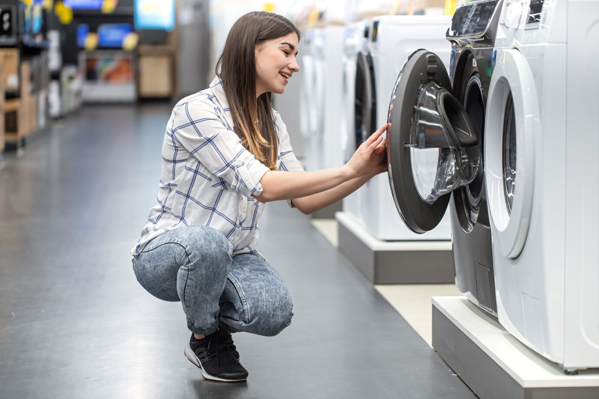 Eine Frau schaut sich eine Waschmaschine in einem Fachgeschäft an.