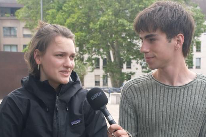 Eine Frau und ein Mann. Der Mann interviewt die Frau, er hält ein Mikrofon in der Hand.