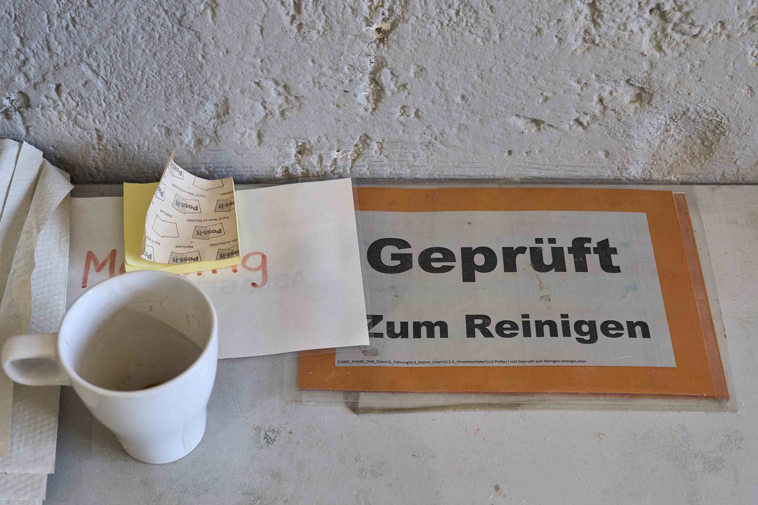 Eine Kaffeetasse, ein Schild, Post-its und Blätter.